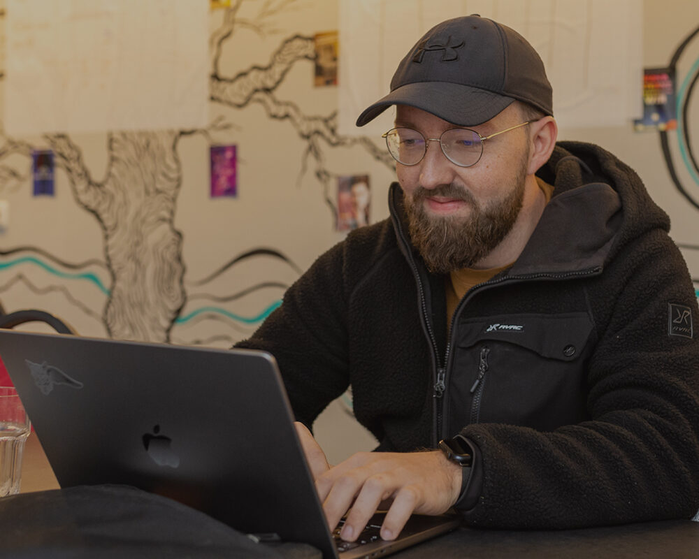 Frederick sitzt vor seinem Laptop und tippt auf der Tastatur.